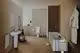 Badezimmeransicht mit Waschbecken, WC und Badewanne, ausgestattet mit einer Bürstengarnitur aus gebürstetem Edelstahl von Ideal Standard. Helle Wände und minimalistische Einrichtung.